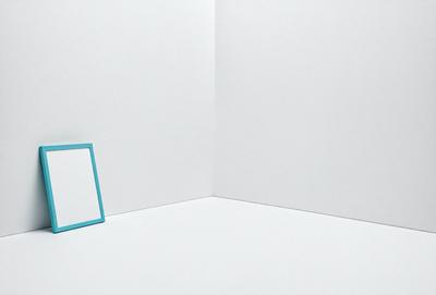 The primary subject of the image is a small blue square, which is placed on a white wall. The setting is a simple white wall, and the visual style appears to be a photo. The colors and mood of the image are predominantly white and blue, creating a clean and calm atmosphere.