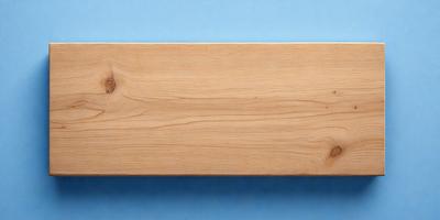 The primary subject of the image is a wooden board, which is the main object in the scene. The setting is a blue surface, possibly a table or a wall. The visual style of the image is a photo, capturing the wooden board in its natural environment. The colors in the image are predominantly blue, creating a calm and serene atmosphere.