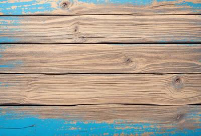 The primary subject of the image is a wooden plank with a blue background. The setting appears to be a wooden surface, possibly a table or a wall. The visual style of the image is a photo, capturing the wooden plank and its surroundings. The colors in the image are predominantly blue and brown, creating a calm and natural atmosphere.