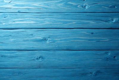The primary subject of the image is a blue wooden wall. The setting is a room with a blue wooden wall as the main focus. The visual style is a photo of a wooden wall. The dominant colors are blue and white, creating a calm and serene atmosphere.