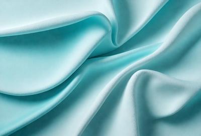 The primary subject of the image is a piece of blue fabric, which is the main object, scene, or focus of the image. The setting or background of the image is a blue sheet, which is visible. The visual style of the image is a photo, as it is a real-life photograph of the blue fabric. The dominant colors in the image are blue, and the overall atmosphere is calm and serene.