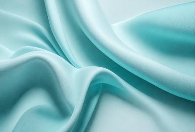 The primary subject of the image is a blue fabric, which is the main object, scene, or focus of the image. The setting or background is a white surface, and the visual style is a photo. The dominant colors in the image are blue and white, creating a calm and serene atmosphere.