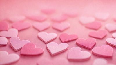 The primary subject of the image is a collection of pink heart-shaped stickers. The setting is a pink background, which creates a warm and inviting atmosphere. The visual style is a close-up of the heart stickers, showcasing their details and texture. The colors and mood of the image are predominantly pink, which evokes feelings of love, affection, and warmth.