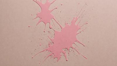 The primary subject of the image is a pink substance, which appears to be a mixture of paint and water, spreading across a surface. The setting is a table, and the visual style is a close-up of the pink substance. The colors and mood of the image are predominantly pink, creating a warm and vibrant atmosphere.