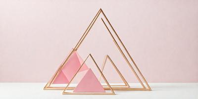 The primary subject of the image is a triangular structure made of wood and pink material. The structure is placed on a white surface, which serves as the background. The visual style of the image is a combination of photo and digital art, as it appears to be a photograph of a digital art piece. The colors and mood of the image are predominantly pink, giving it a warm and inviting atmosphere.