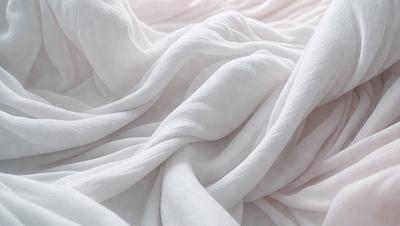 The primary subject of the image is a white sheet or blanket, which is the main object, scene, or focus of the image. The setting or background is a bed, and the visual style is a photo. The colors and mood of the image are predominantly white, giving it a clean and serene atmosphere.
