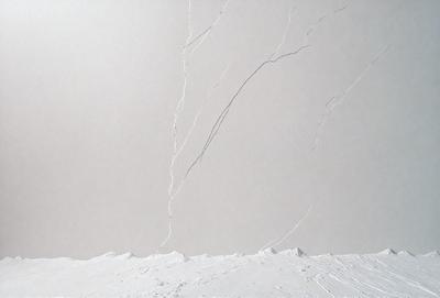 The primary subject of the image is a large, white wall with a crack in it. The setting is a snowy landscape, with a mountain visible in the background. The visual style is a combination of photo and digital art, creating a unique and striking image. The dominant colors are white and gray, with the crack in the wall adding a contrasting element to the overall atmosphere.