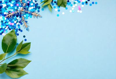 The primary subject of the image is a blue background with a leaf pattern. The leaf pattern is made up of green leaves and blue snowflakes. The setting is a blue surface, and the visual style is a patterned background. The colors and mood of the image are predominantly blue and green, creating a calm and serene atmosphere.