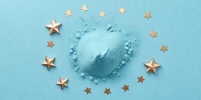 The primary subject of the image is a blue star-shaped object, which appears to be a piece of cake or a decoration. The setting is a blue surface, possibly a table or a wall. The visual style is a combination of photo and digital art, creating a unique and eye-catching design. The colors and mood of the image are predominantly blue, with a touch of gold from the stars, giving it a calm and serene atmosphere.
