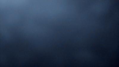 The primary subject of the image is a dark blue sky with a few clouds. The setting is a cloudy day, and the visual style is a photo. The colors and mood of the image are predominantly dark and moody, with the blue sky and clouds creating a dramatic atmosphere.