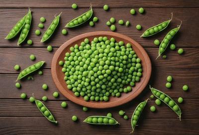 The primary subject of the image is a wooden bowl filled with green peas. The bowl is placed on a wooden table, which serves as the setting for the scene. The visual style of the image is a close-up of the bowl of peas, showcasing the vibrant green color of the peas. The colors and mood of the image are lively and fresh, as the green peas are the main focus of the scene.
