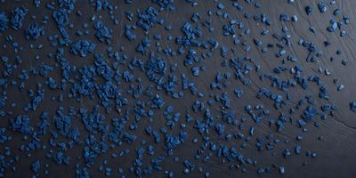 The primary subject of the image is a close-up of a blue surface, possibly a table or a wall, with a pattern of blue and white dots. The setting appears to be a dark room, and the visual style is a close-up of the blue surface. The colors and mood of the image are predominantly blue, creating a calm and serene atmosphere.