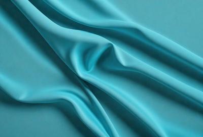 The primary subject of the image is a blue fabric, which is the main object, scene, or focus of the image. The setting or background is a blue surface, which complements the blue fabric. The visual style of the image is a photo, as it captures the fabric's texture and details. The colors and mood of the image are predominantly blue, creating a calm and serene atmosphere.
