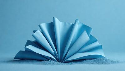 The primary subject of the image is a blue paper flower. The setting is a blue background, which creates a visually appealing contrast with the paper flower. The visual style is a combination of photo and digital art, as the paper flower appears to be a realistic representation of a flower, yet it is made of paper. The colors and mood of the image are predominantly blue, giving it a calm and serene atmosphere.