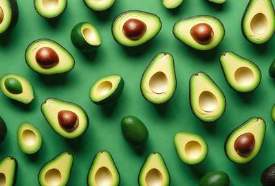 The primary subject of the image is a large number of avocados, which are arranged in a pattern on a green surface. The avocados are of various sizes and are spread across the entire image. The setting appears to be a table or a countertop, and the visual style is a close-up of the avocados, showcasing their details and textures. The colors and mood of the image are predominantly green, which is the color of the avocados and the surface they are placed on.