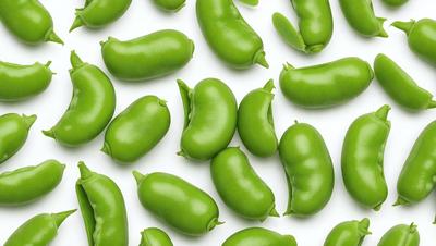 The primary subject of the image is a large group of green beans, which are the main objects in the scene. The beans are arranged in a pattern, covering the entire image. The setting is a white background, which provides a clean and uncluttered look to the image. The visual style is a close-up of the green beans, showcasing their texture and details. The colors and mood of the image are predominantly green, giving it a fresh and vibrant appearance.