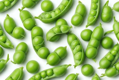 The primary subject of the image is a large group of green peas. They are arranged in various positions, covering the entire frame. The setting is a white background, which provides a clean and uncluttered look. The visual style is a close-up of the peas, showcasing their details and texture. The colors and mood of the image are predominantly green, giving it a fresh and natural feel.