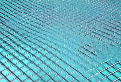 The primary subject of the image is a blue, textured surface, which appears to be a tile or a piece of glass. The setting is a room with a blue-tinted atmosphere. The visual style is a close-up of the blue surface, showcasing its texture and color. The colors and mood of the image are predominantly blue, creating a calm and serene atmosphere.