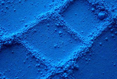 The primary subject of the image is a blue substance, possibly a powder or a liquid, with a pattern of small bubbles or spheres. The setting appears to be a blue surface, possibly a table or a countertop. The visual style of the image is a close-up of the blue substance, showcasing its texture and the pattern of the bubbles or spheres. The colors and mood of the image are predominantly blue, creating a calm and soothing atmosphere.