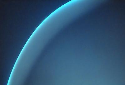 The primary subject of the image is a blue, curved surface, which appears to be a part of a spacecraft. The setting is a dark, blue background, which contrasts with the blue surface. The visual style is a combination of photo and digital art, creating a unique and captivating image. The dominant colors are blue, with a few other colors present in the background. The overall atmosphere is one of mystery and intrigue, as the viewer is left to wonder about the purpose and function of the spacecraft.