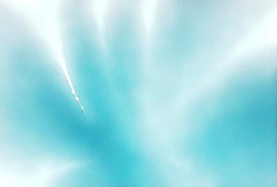 The primary subject of the image is a bright blue sky with a trail of light streaking through it. The sky appears to be cloudless, and the light streaking through it creates a sense of motion and dynamism. The visual style of the image is a combination of photo and digital art, as it captures the beauty of the sky and the light trail in a visually appealing manner. The colors and mood of the image are predominantly blue, creating a serene and peaceful atmosphere.