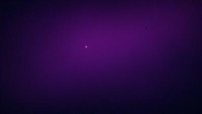 The image is a purple background with a small white dot in the center. The purple color creates a unique and visually striking scene. The white dot stands out against the purple background, drawing attention to it. The overall atmosphere of the image is calm and serene, with the purple hue giving it a slightly mysterious or dreamy quality.