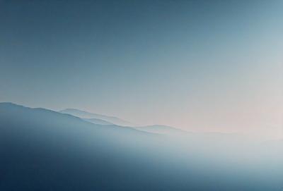 The primary subject of the image is a mountain range, with a blue sky serving as the backdrop. The visual style appears to be a photo, capturing the majestic beauty of the mountains. The colors and mood of the image are predominantly blue, creating a serene and peaceful atmosphere.