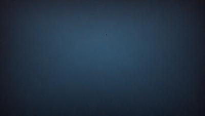 The primary subject of the image is a blue sky with a single dot in the middle of it. The sky appears to be a deep shade of blue, and the dot is located towards the center of the image. The setting is a vast, open space with no other objects or elements visible. The visual style of the image is a simple, minimalist representation of the sky. The colors and mood of the image are calm and serene, with the deep blue sky evoking a sense of tranquility and vastness.