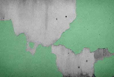The primary subject of the image is a green wall with white spots and a peeling paint effect. The setting is a room with a green background. The visual style is a combination of a photo and digital art, creating a unique and artistic appearance. The dominant colors are green and white, with the white spots adding texture and depth to the green wall. The overall atmosphere is one of creativity and artistic expression.