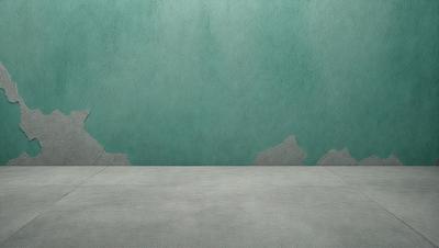 The primary subject of the image is a wall with a green color. The setting is a room with a concrete floor. The visual style is a photo, and the colors and mood are predominantly green, creating a calm and serene atmosphere.
