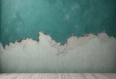 The primary subject of the image is a large, blue wall with peeling paint. The setting is a room with a wooden floor. The visual style is a photo, and the dominant colors are blue and white. The overall atmosphere is somewhat deteriorated or aged, possibly due to the peeling paint and the presence of a cracked wall.