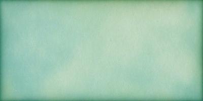 The primary subject of the image is a large, white sheet of paper. The setting is a room with a green background. The visual style is a close-up of the paper, showcasing its texture and color. The colors and mood of the image are predominantly green, creating a calm and serene atmosphere.