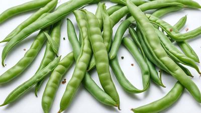 The primary subject of the image is a large group of green beans, which are the main objects in the scene. The beans are displayed on a white surface, possibly a table or a counter. The visual style of the image is a close-up of the green beans, showcasing their texture and details. The colors in the image are predominantly green, which gives the scene a fresh and vibrant atmosphere.