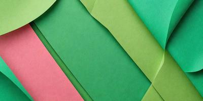 The image features a close-up of green and pink paper, possibly a piece of fabric or a patterned paper. The green and pink colors create a vibrant and lively atmosphere. The paper appears to be a part of a larger collection, as it is cut into smaller pieces and stacked together. The visual style of the image suggests that it could be a photo or a digital art piece, showcasing the intricate details of the paper.