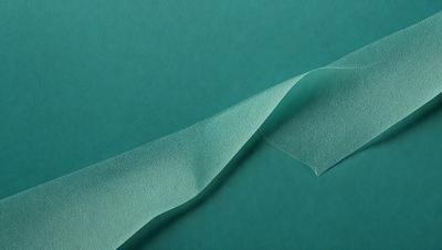 The primary subject of the image is a piece of green leather, which is the main object in the scene. The setting is a green background, and the visual style appears to be a photo. The colors in the image are predominantly green, creating a calm and natural atmosphere.