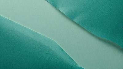 The primary subject of the image is a green sheet of paper. The setting is a table, and the visual style is a photo. The colors and mood of the image are predominantly green, creating a calm and soothing atmosphere.