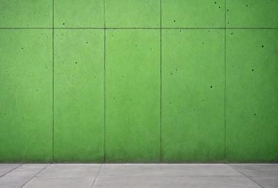 The primary subject of the image is a green wall with a pattern of holes. The setting is a concrete wall, and the visual style appears to be a photo. The dominant colors are green and white, creating a calm and soothing atmosphere.