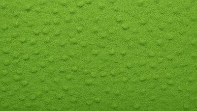 The primary subject of the image is a green surface with a pattern of small circles. The setting appears to be a room with a green wall, and the visual style is a close-up of the green surface. The dominant colors are green and white, creating a calm and soothing atmosphere.