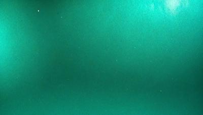 The primary subject of the image is a green background. The setting is a dark room, and the visual style appears to be a photo. The colors and mood of the image are predominantly green, creating a calm and serene atmosphere.