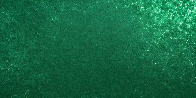 The primary subject of the image is a green background with a pattern of glittering stars. The setting is a dark background, which contrasts with the bright green color of the stars. The visual style appears to be a combination of a photo and digital art, as the stars have a glittering effect that is not typically found in a photo. The colors and mood of the image are vibrant and lively, with the green background and glittering stars creating a sense of depth and movement.