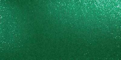 The primary subject of the image is a green background with a glittery, shiny appearance. The setting is a dark room, and the visual style is a close-up of the green background. The colors and mood of the image are predominantly green, with a slightly shiny and glittery effect.