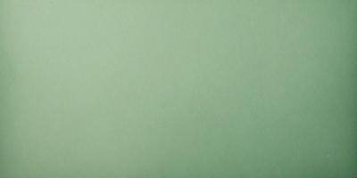 The primary subject of the image is a large, empty white wall. The setting is a room with a green background, which creates a clean and minimalist atmosphere. The visual style is a close-up of the wall, emphasizing its texture and simplicity. The colors and mood of the image are predominantly white and green, giving it a calm and serene appearance.