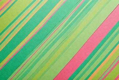 The primary subject of the image is a green and pink striped paper. The setting is a table, and the visual style is a patterned paper. The colors and mood of the image are predominantly green and pink, creating a vibrant and lively atmosphere.