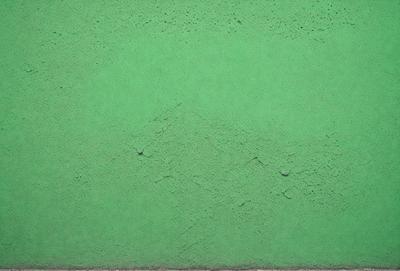The primary subject of the image is a green wall with a texture that resembles a mountain. The setting is an indoor environment, possibly a room or a building. The visual style is a close-up of the green wall, showcasing its unique texture. The colors and mood of the image are predominantly green, giving it a calm and serene atmosphere.