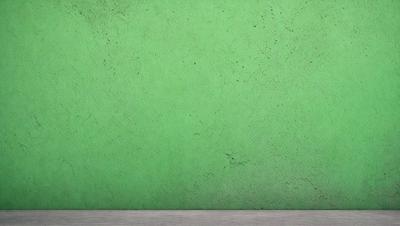 The primary subject of the image is a green wall with a textured surface. The setting is a room with a table in the foreground. The visual style is a photo, and the dominant colors are green and white. The overall atmosphere is clean and fresh, with a hint of natural texture.