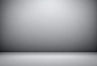 The primary subject of the image is a large, empty white wall. The setting is a room with a gray background, which creates a clean and minimalist atmosphere. The visual style is a photo, capturing the stark contrast between the white wall and the gray background. The colors and mood of the image are predominantly white and gray, giving it a calm and serene appearance.