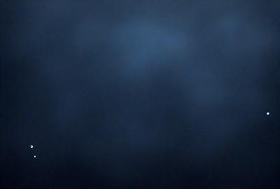The primary subject of the image is a dark blue sky with a few clouds. The setting is a vast, open space with no visible landmarks or objects. The visual style is a natural, outdoor scene. The colors and mood are predominantly dark and moody, with the blue sky and clouds creating a sense of depth and vastness.