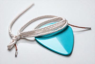 The primary subject of the image is a blue guitar pick. The setting is a white background, and the visual style appears to be a photo. The dominant colors are blue and white, creating a calm and soothing atmosphere.