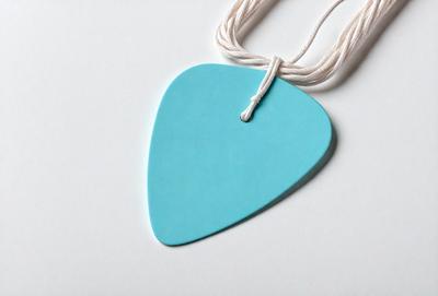 The primary subject of the image is a blue heart-shaped guitar pick. The setting is a white background, and the visual style appears to be a photo. The dominant colors are blue and white, creating a calm and serene atmosphere.