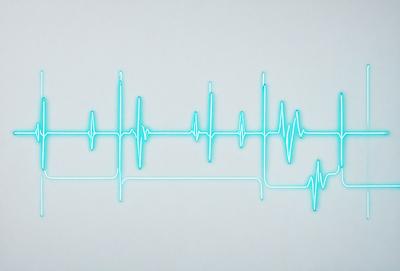 The primary subject of the image is a neon-colored heartbeat, which is displayed on a white background. The visual style of the image is digital art, as it appears to be a computer-generated or digitally edited illustration. The colors and mood of the image are predominantly neon and futuristic, creating a unique and eye-catching design.
